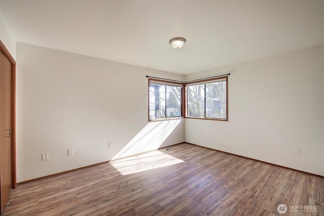 unfurnished room with baseboards and wood finished floors