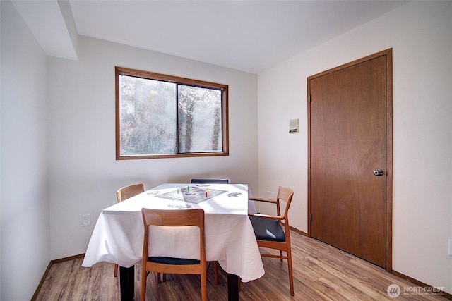 dining area featuring light wood finished floors and baseboards