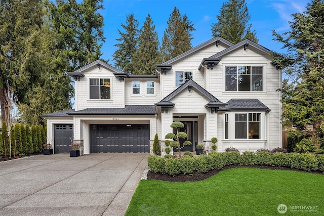 view of front of house with a garage, a front yard, concrete driveway, and roof with shingles