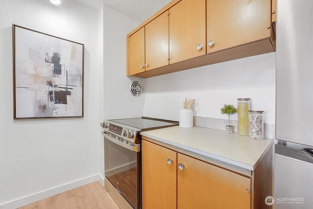 kitchen featuring light wood finished floors, visible vents, baseboards, stainless steel appliances, and light countertops