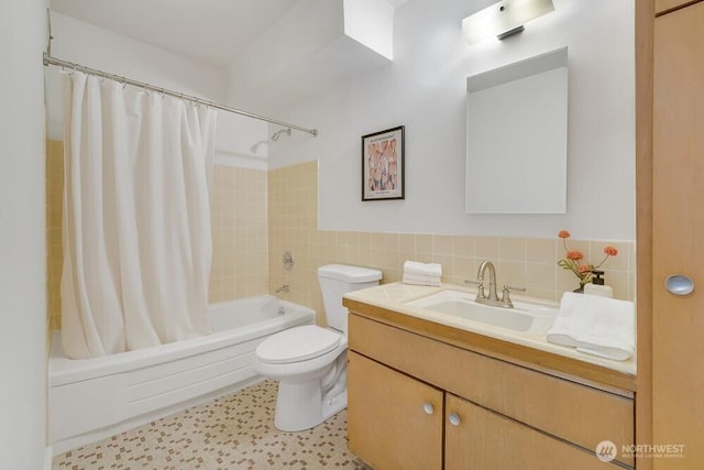 bathroom with toilet, a wainscoted wall, vanity, tile walls, and shower / bath combination with curtain