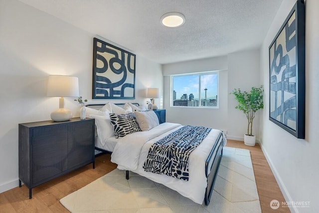 bedroom featuring a textured ceiling, baseboards, and wood finished floors