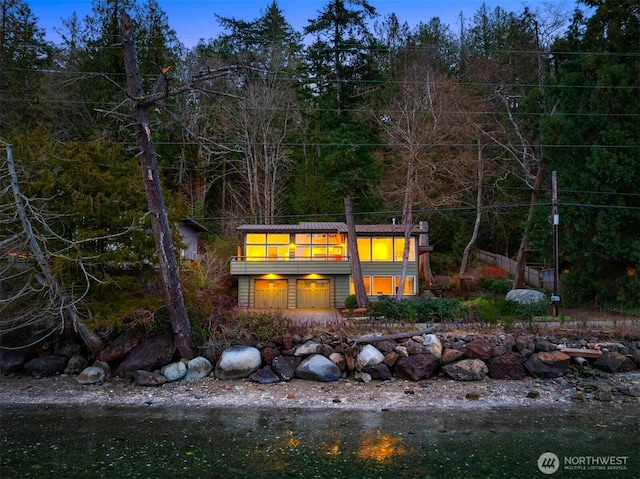 rear view of property with a balcony and a forest view