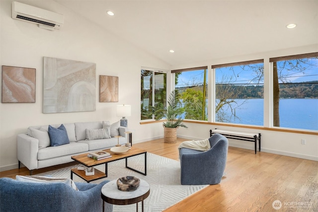 living room featuring a wall unit AC, recessed lighting, a water view, light wood-style floors, and vaulted ceiling