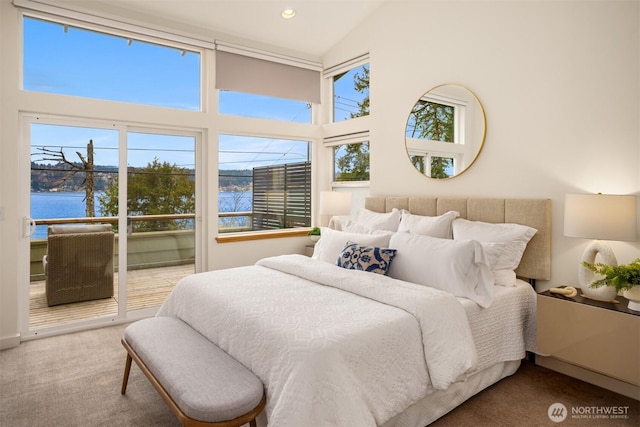 carpeted bedroom with a water view, a towering ceiling, and recessed lighting