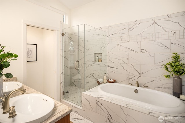 full bath with marble finish floor, a garden tub, a marble finish shower, double vanity, and a sink