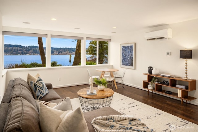 living room with recessed lighting, a water view, wood finished floors, baseboards, and an AC wall unit