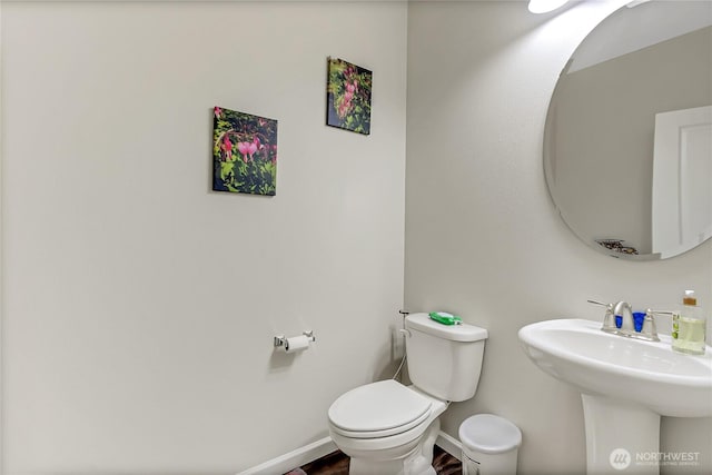 half bathroom featuring a sink, toilet, and baseboards