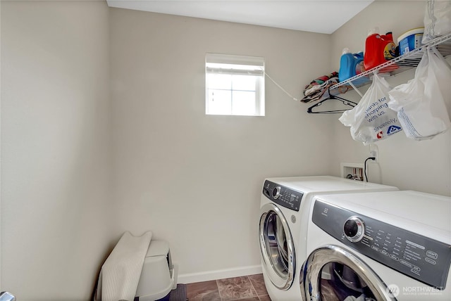 clothes washing area featuring laundry area, baseboards, and washing machine and clothes dryer