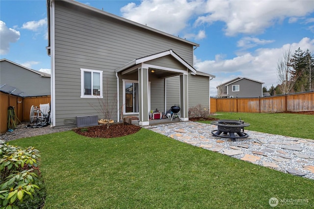 rear view of property featuring an outdoor fire pit, a patio area, a yard, and a fenced backyard