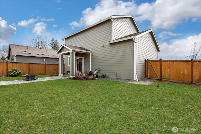 rear view of property featuring a lawn and fence