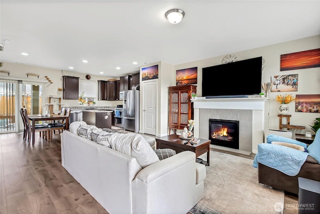 living room featuring a tile fireplace, light wood-style flooring, and recessed lighting