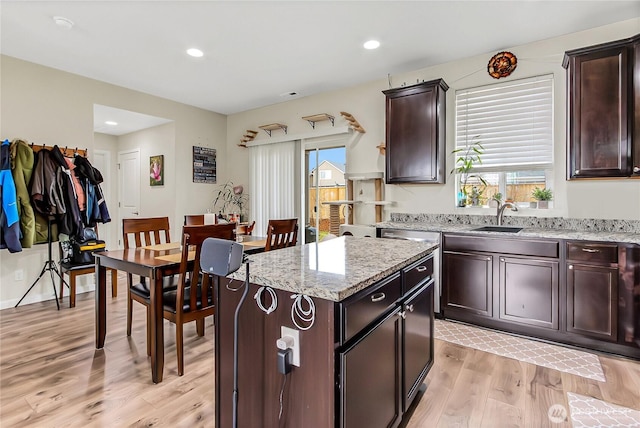 kitchen featuring a wealth of natural light, light wood-type flooring, a center island, and light stone countertops