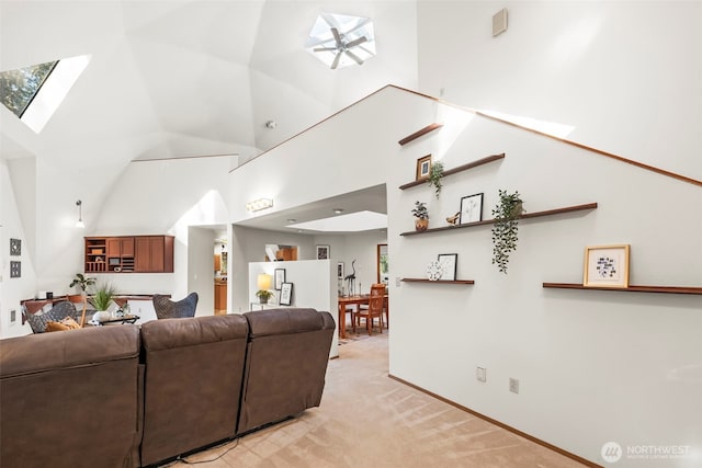 living area featuring a skylight, a high ceiling, and light colored carpet