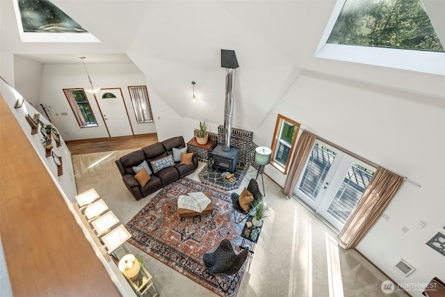 living room with a wood stove, visible vents, vaulted ceiling, and stairs