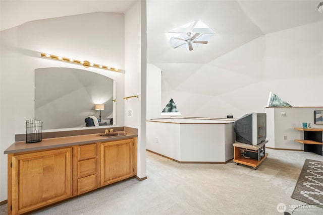 interior space featuring a ceiling fan, vaulted ceiling, vanity, and baseboards