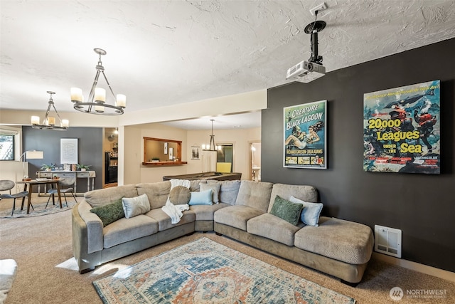 living area with carpet floors, visible vents, a notable chandelier, and a textured ceiling