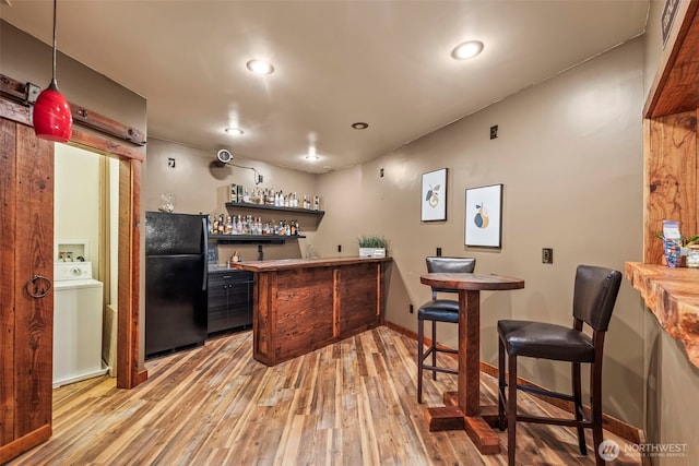 bar with baseboards, indoor bar, freestanding refrigerator, light wood-style floors, and recessed lighting