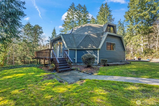 view of front of home with a shingled roof, a gambrel roof, a front yard, a wooden deck, and stairs