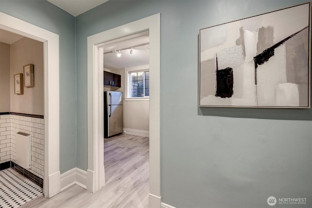 corridor featuring baseboards and light wood finished floors