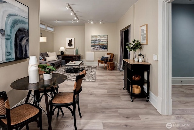 dining area featuring light wood-style floors, track lighting, and baseboards