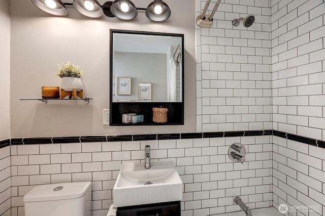 bathroom featuring toilet, a wainscoted wall, a shower, and vanity