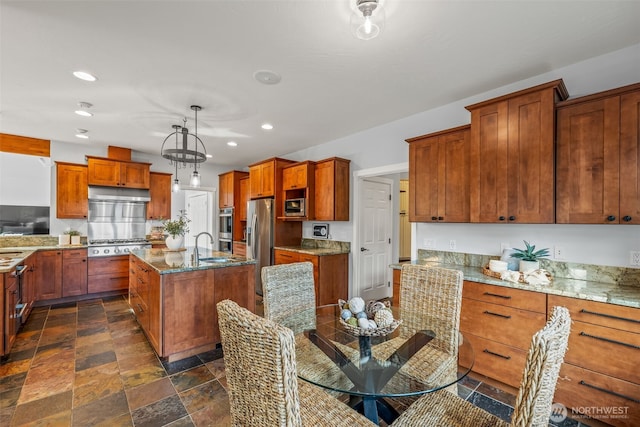 kitchen with light stone countertops, under cabinet range hood, an island with sink, recessed lighting, and stainless steel appliances