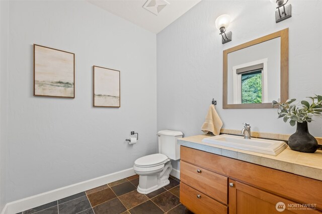 half bathroom featuring tile patterned flooring, visible vents, baseboards, toilet, and vanity