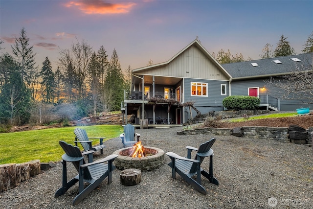 back of house at dusk with an outdoor fire pit and a yard