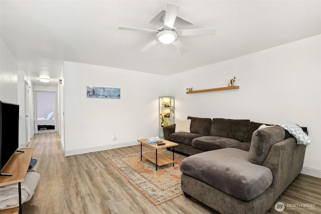 living room featuring a ceiling fan, baseboards, and wood finished floors