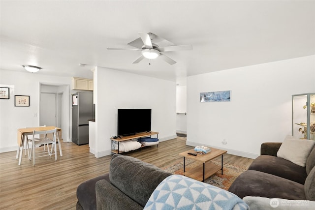 living room with a ceiling fan, light wood-style flooring, and baseboards