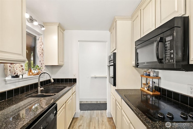 kitchen featuring light wood-type flooring, cream cabinetry, a sink, and black appliances