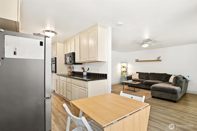 kitchen with ceiling fan, cream cabinets, light wood-style floors, black appliances, and dark countertops