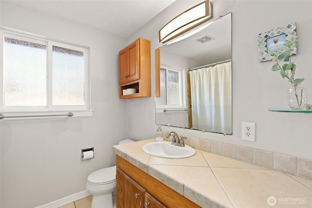 bathroom featuring toilet, plenty of natural light, baseboards, and vanity