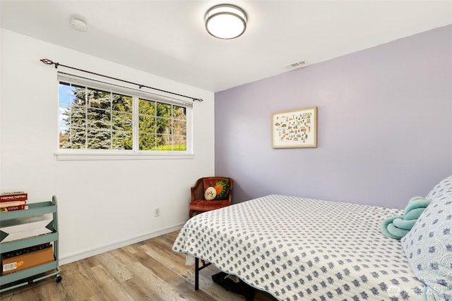 bedroom featuring visible vents, baseboards, and wood finished floors