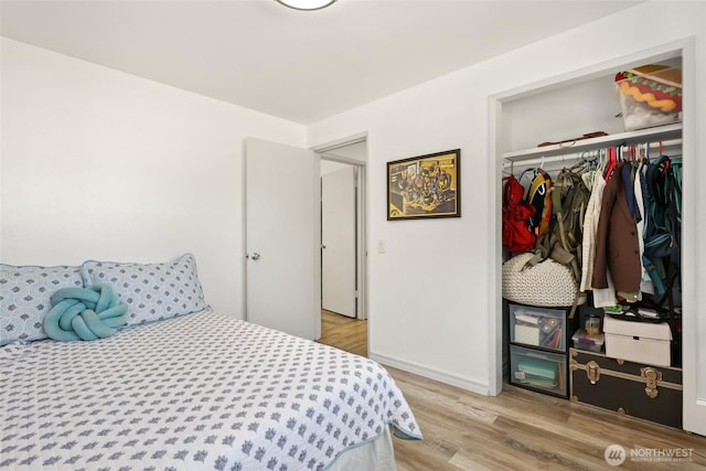 bedroom with light wood-type flooring, a closet, and baseboards