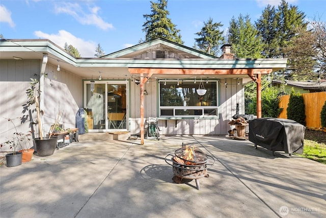 back of property featuring a fire pit, a patio, and fence