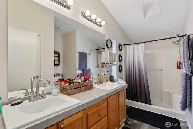 full bathroom featuring lofted ceiling, double vanity, visible vents, and a sink