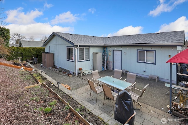 rear view of property with a garden, outdoor dining area, a patio, and roof with shingles