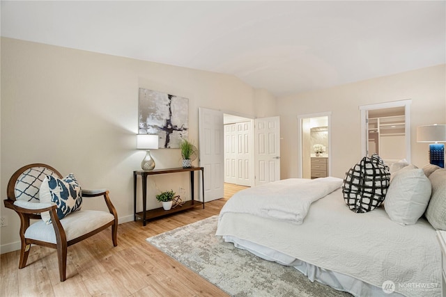 bedroom with lofted ceiling, a closet, baseboards, and light wood-style floors