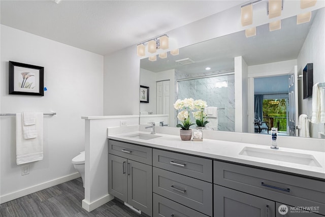 bathroom with toilet, a sink, a marble finish shower, and baseboards