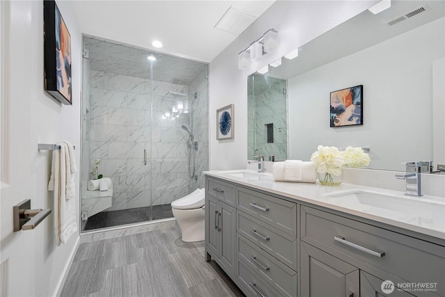 full bath featuring toilet, a marble finish shower, visible vents, and a sink