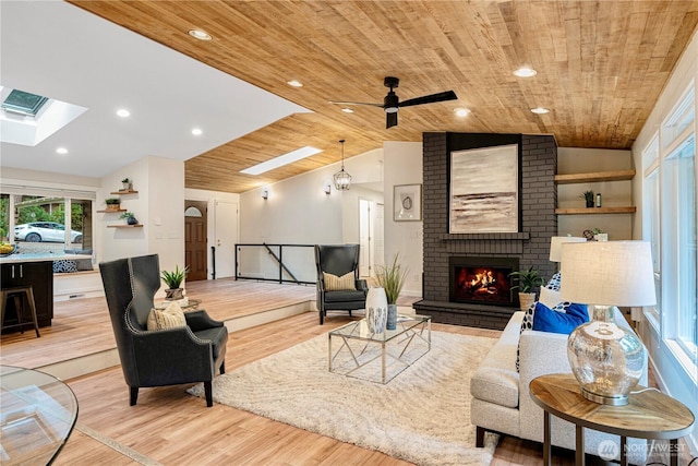 living area with a fireplace, recessed lighting, light wood-style floors, vaulted ceiling with skylight, and wooden ceiling