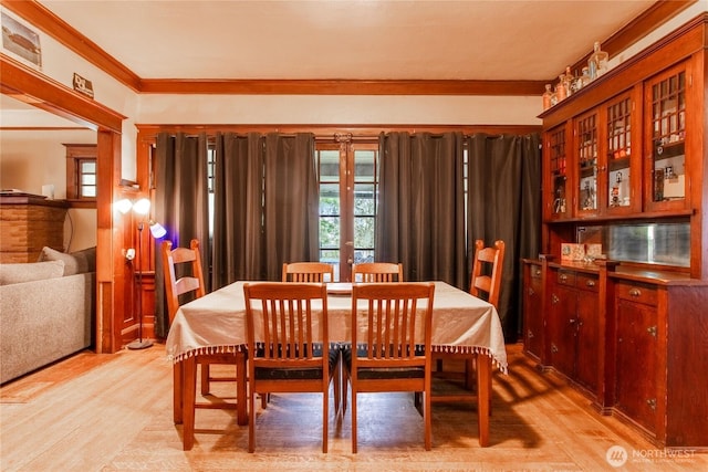 dining space featuring ornamental molding and light wood-style flooring