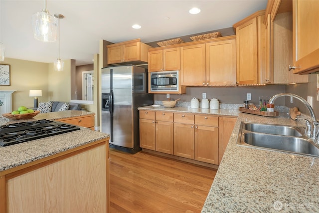 kitchen with light wood finished floors, recessed lighting, hanging light fixtures, stainless steel appliances, and a sink