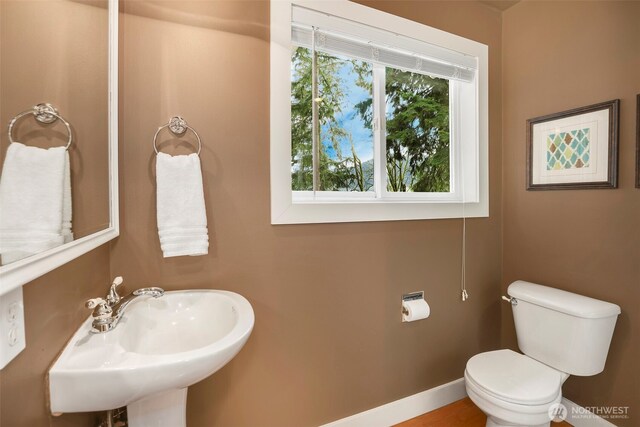 bathroom with toilet, baseboards, and a sink