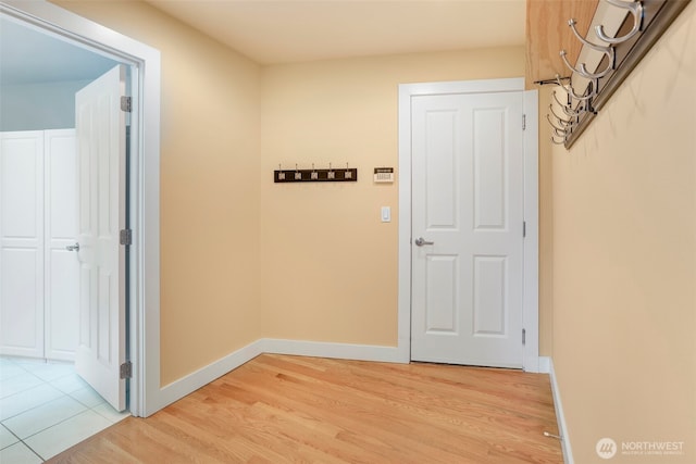 corridor with light wood-type flooring and baseboards