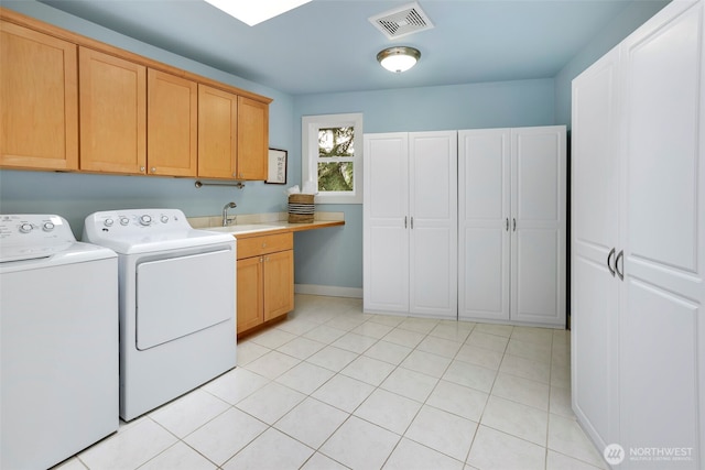 clothes washing area featuring visible vents, a sink, washing machine and dryer, cabinet space, and baseboards