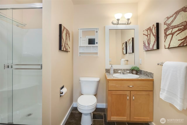 bathroom with a shower stall, toilet, vanity, and baseboards