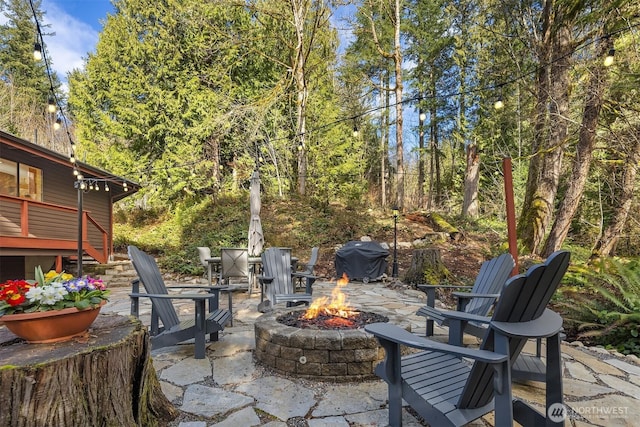 view of patio / terrace with stairway, a grill, an outdoor fire pit, and a view of trees